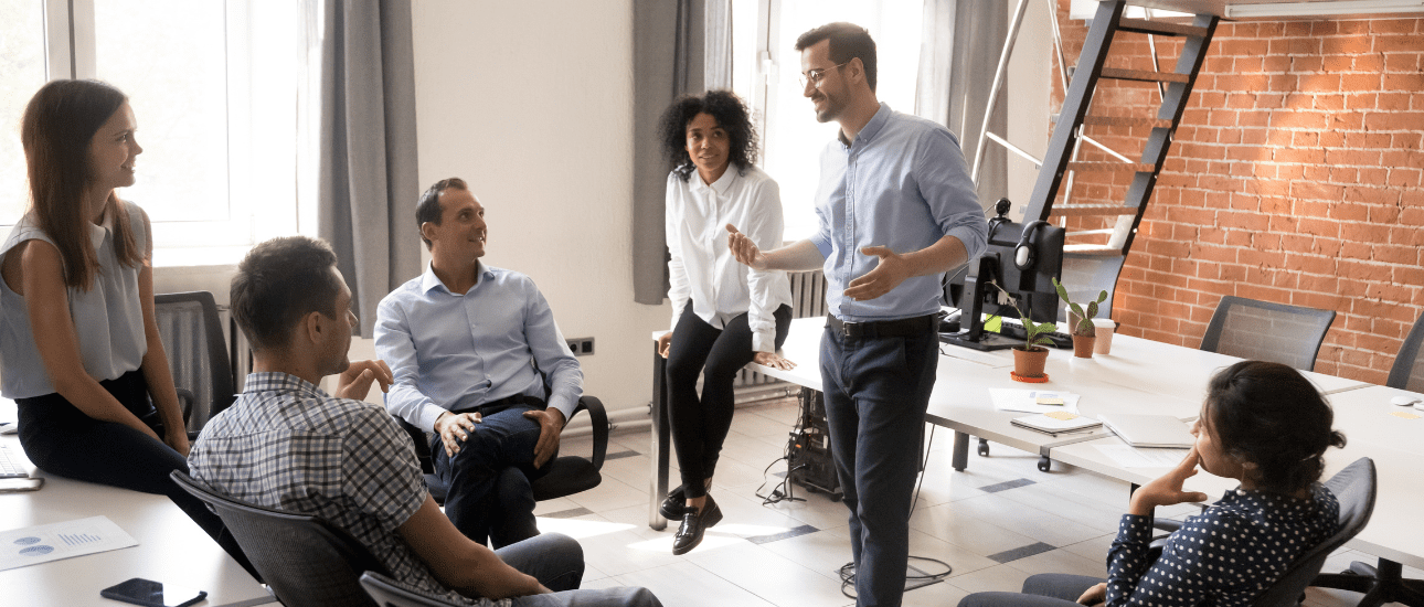 A group of people listening to a men talking in an office